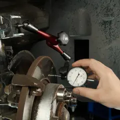 Mechanik sprawdza bicie przy hamowaniu, używając czujnika zegarowego do oceny prostych tarcz hamulcowych.