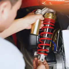 Mechanik wymienia czerwoną sprężynę amortyzatora w motocyklu.
