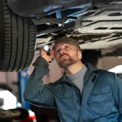 Mechanik bada podwozie auta, szukając uszkodzone jarzmo zacisku objawy.
