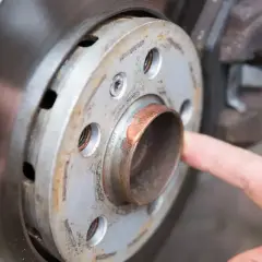 Zbliżenie na piastę koła samochodu z widocznym smarem miedzianym na metalowej powierzchni.