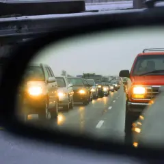 Widok z lusterka samochodowego na korek uliczny i inne pojazdy.