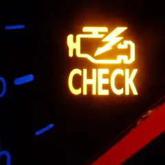 Żółta kontrolka silnika z napisem "CHECK" na desce rozdzielczej samochodu.