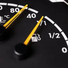 Zbliżenie na deskę rozdzielczą samochodu: wskaźnik temperatury płynu chłodniczego i wskaźnik paliwa.
