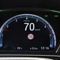 Cyfrowy prędkościomierz samochodu pokazuje 70 km/h, obok wskaźnik temperatury i zegar.