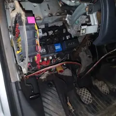 Widok na skrzynkę z bezpiecznikami i przekaźnikami w Audi A4 B6. Widać kolorowe bezpieczniki i kable.