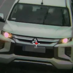 Biały pickup jedzie zderzakiem do przodu, z czerwonym krzyżem na grillu.