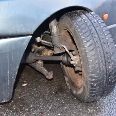 Uszkodzony sworzeń wahacza w samochodzie, widoczny przy kole.
