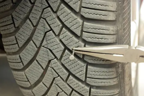 Wyjmowanie gwoździa z opony. Sprawdź, czy Twoja gwarancja na opony obejmuje takie uszkodzenia.