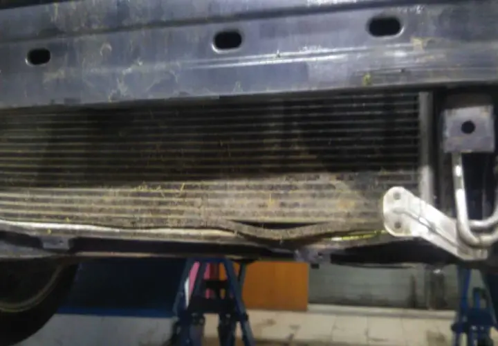 Uszkodzony skraplacz klimatyzacji objawy: zgięte żeberka, widoczne uszkodzenia mechaniczne.