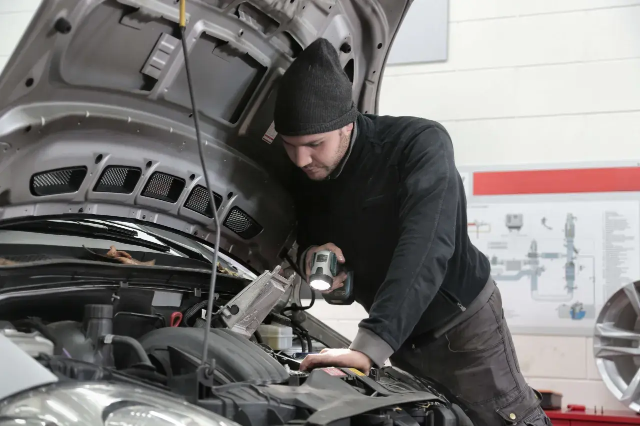 Mechanik z latarką bada silnik, zastanawiając się, jak długo jeszcze wytrzyma stukający przegub.