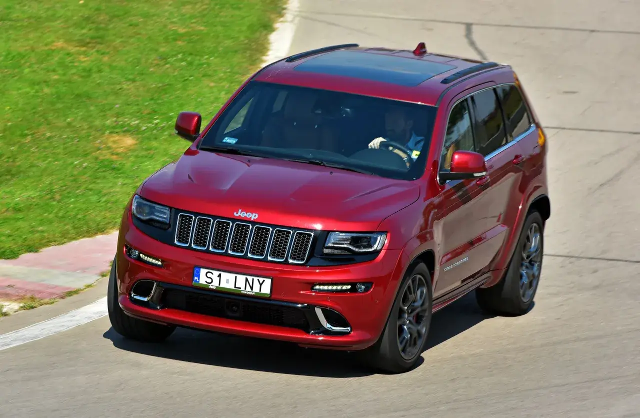 Czerwony Jeep Grand Cherokee na torze. Na tablicy rejestracyjnej widnieje napis S1 LNY. Ile liter ma własna rejestracja?