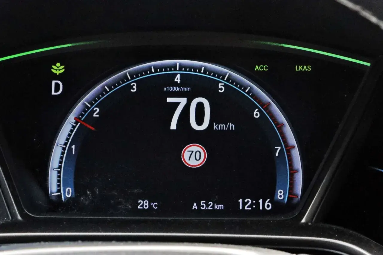 Cyfrowy prędkościomierz samochodu pokazuje 70 km/h, obok wskaźnik temperatury i zegar.