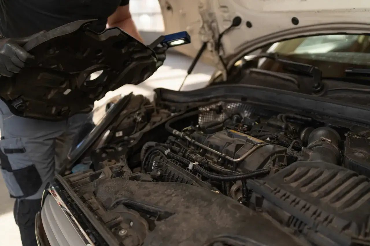 Mechanik sprawdza silnik po jednorazowym przegrzaniu. Widać elementy silnika i narzędzia.